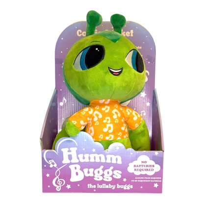 Green plush toy with a purple packaging background, featuring the brand 'Humm Buggs'.