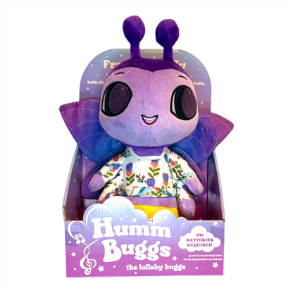 Purple plush toy with a smiling face and floral shirt in packaging, labeled 'Humm Buggs'.